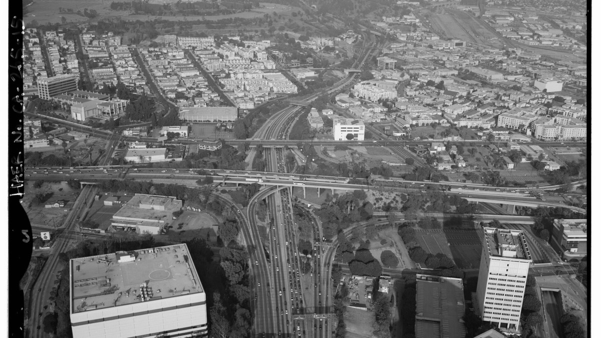 Black-and-white aerial photo of a four-level highway interchange with ramps crossing and diverging, standing in for three companies taking three different routes to the personal agent (Wikimedia Commons, public domain, HAER archive)