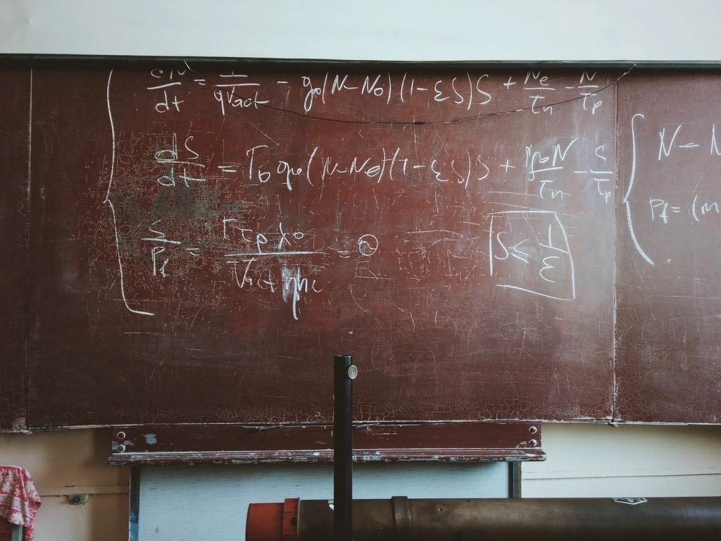 Differential equations worked out in white chalk on a worn blackboard