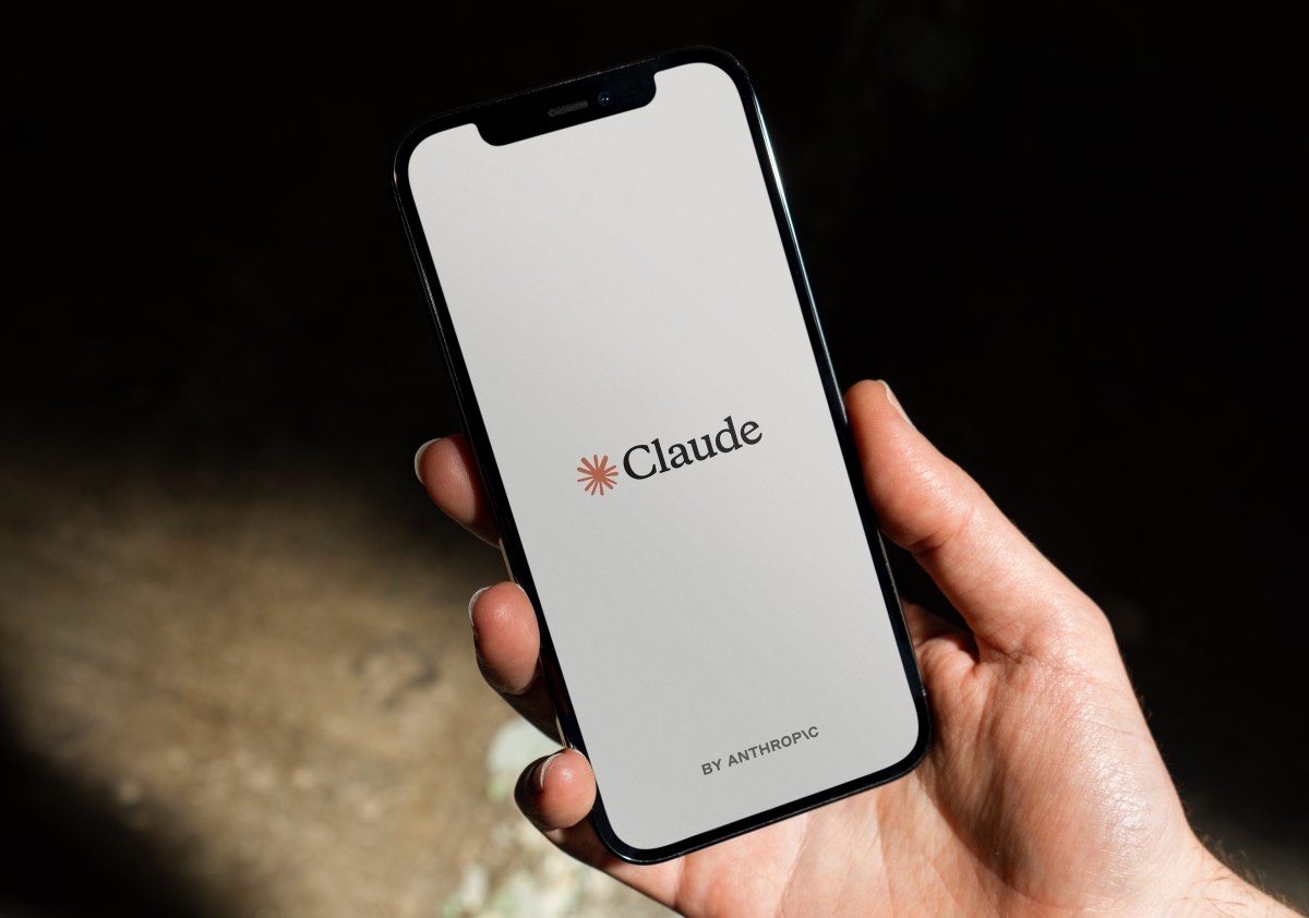 手持手机显示 Claude 应用启动页