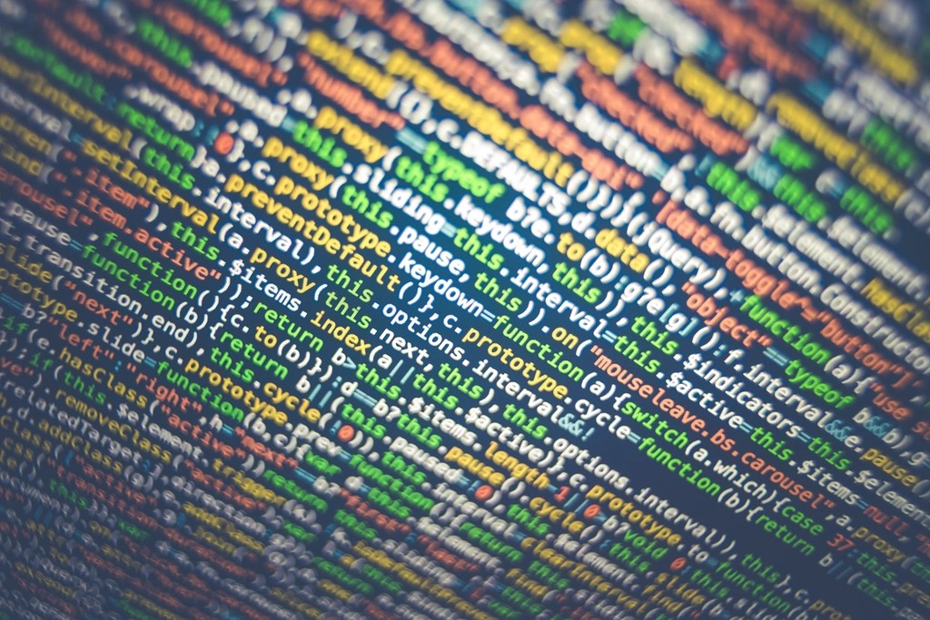 Tilted, softly blurred close-up of colorful source code lines on a dark screen