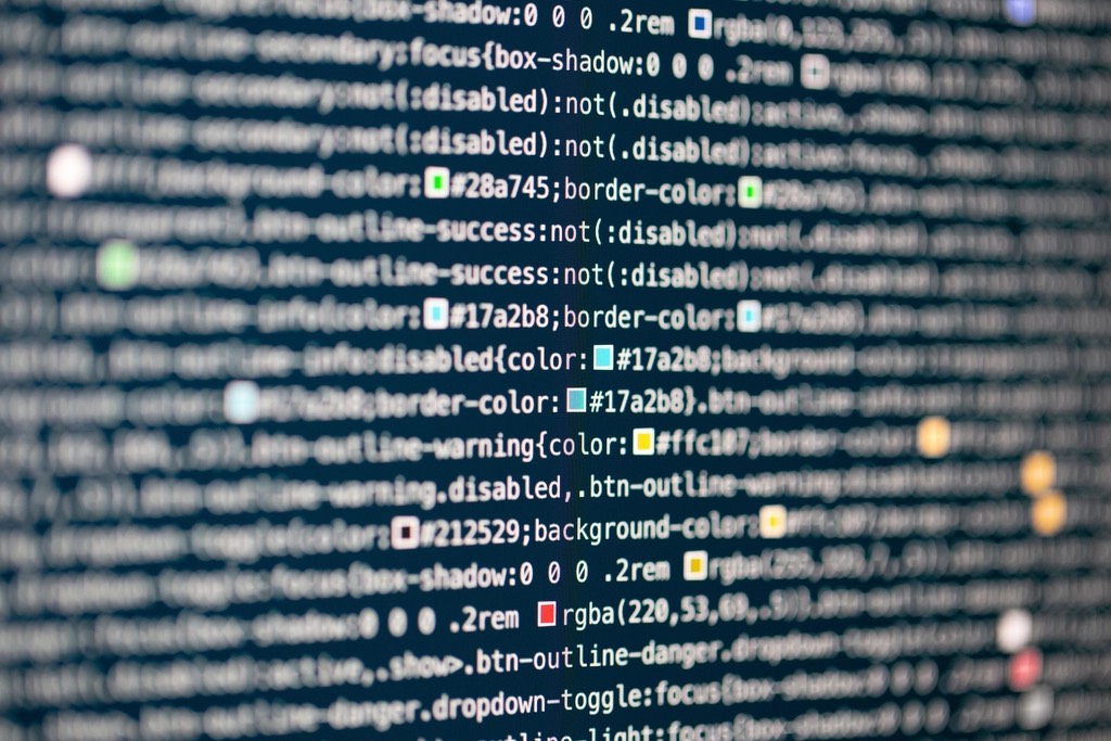 Blurred code fills a computer screen, dotted with colored lights