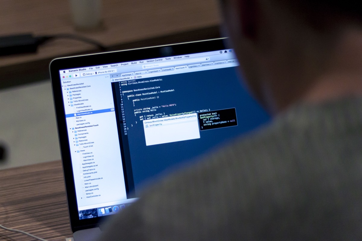 A laptop screen displays a code editor and development toolbars.