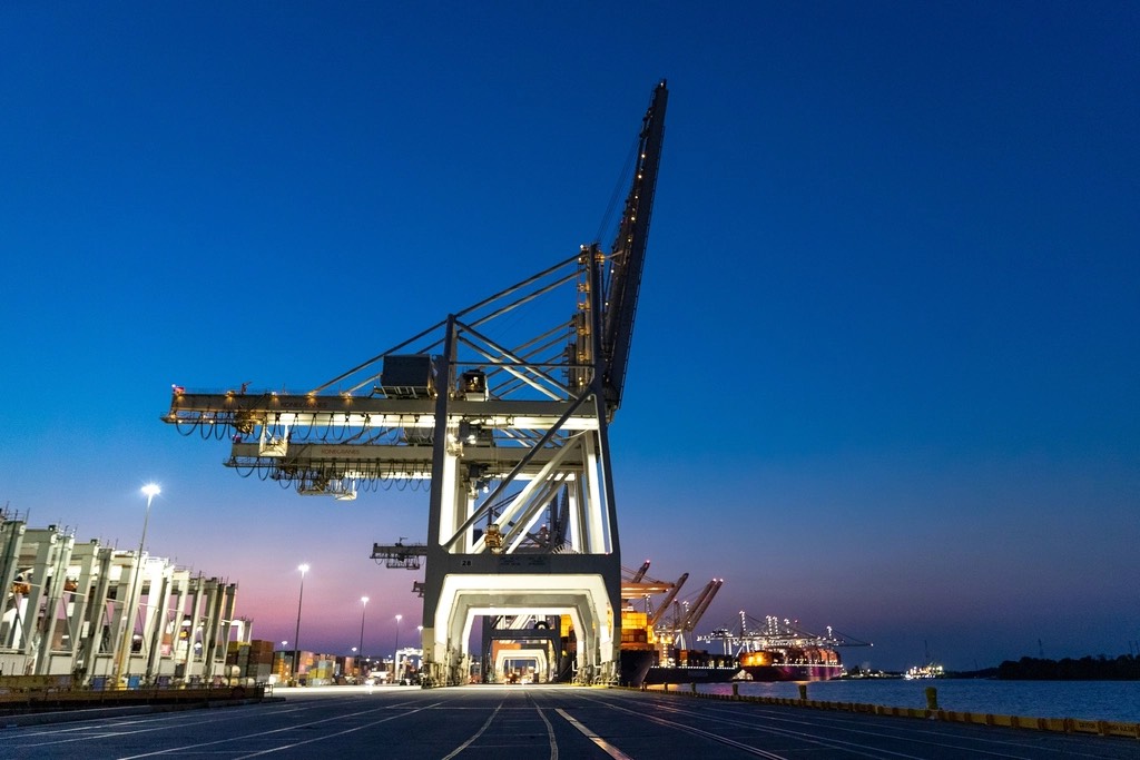 Illuminated container cranes at a port at dusk