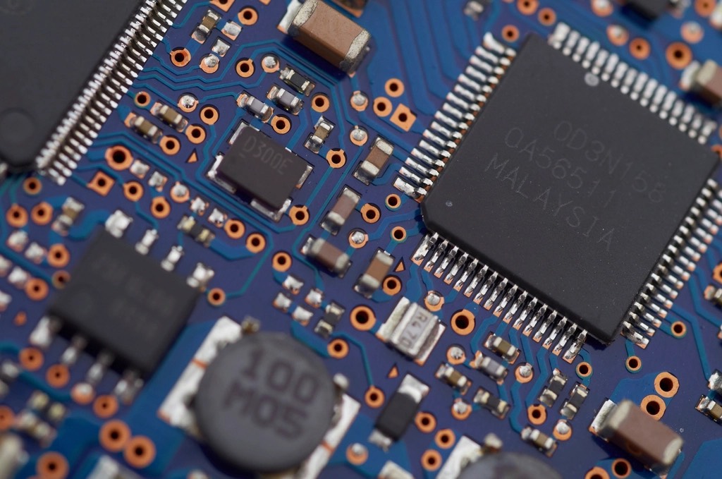 Macro photograph of a blue circuit board, chips and components in focus