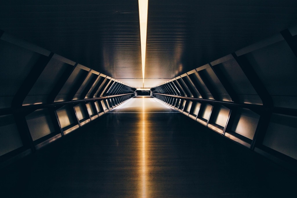 A straight pedestrian tunnel, a light strip on its ceiling running to the vanishing point