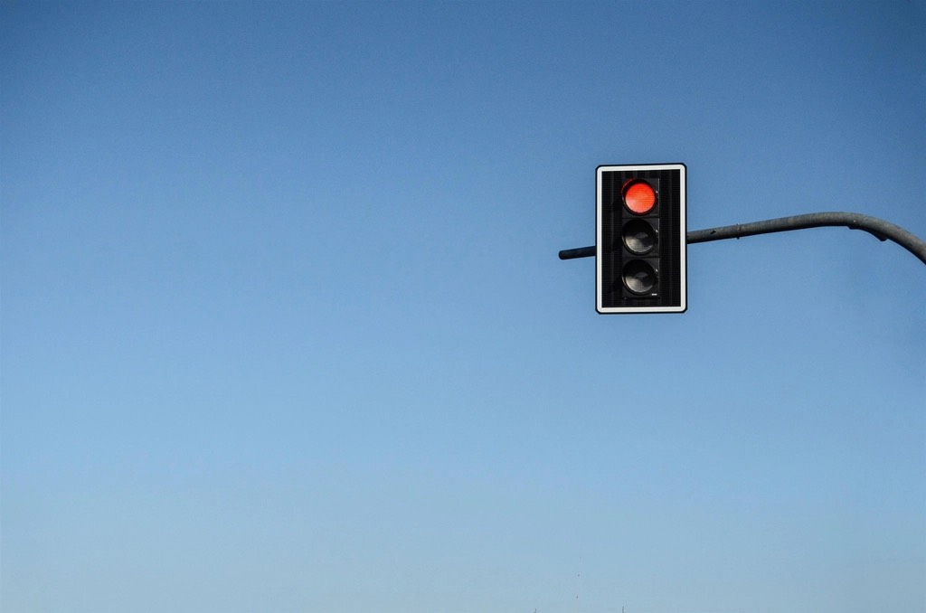 A traffic light showing red against a blue sky