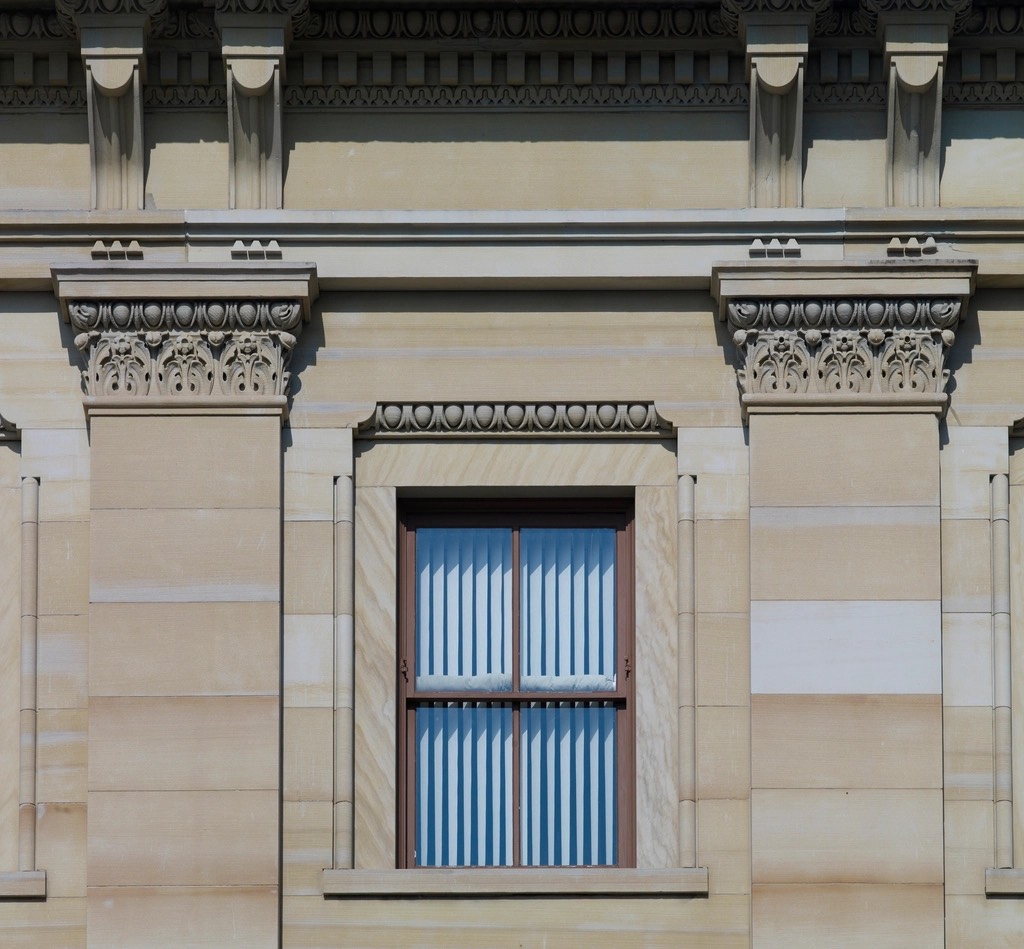 Carved column capitals and a window on a federal building’s stone facade