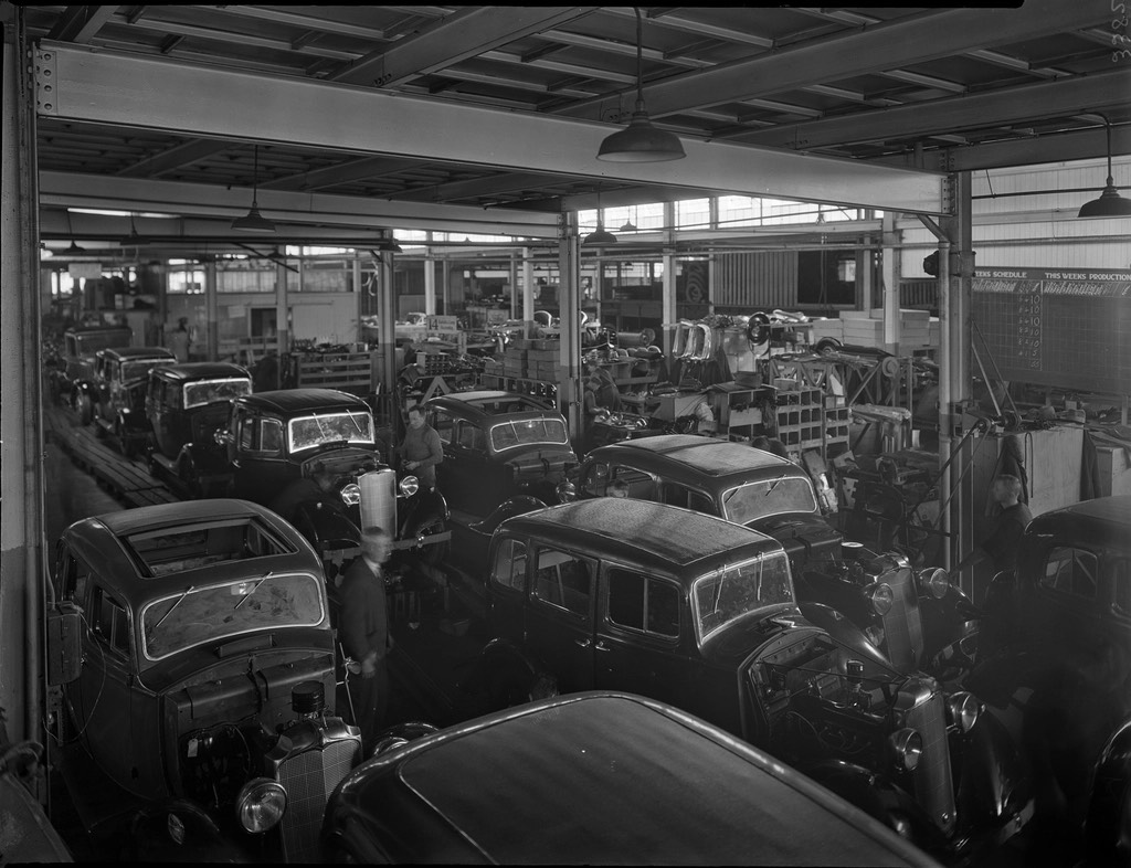 An archive photograph of a car assembly hall, rows of bodies lined up along the tracks