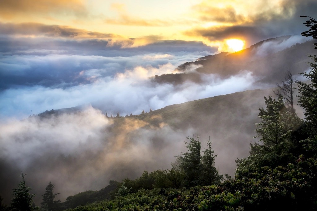 A mountain ridge above a sea of clouds at sunrise